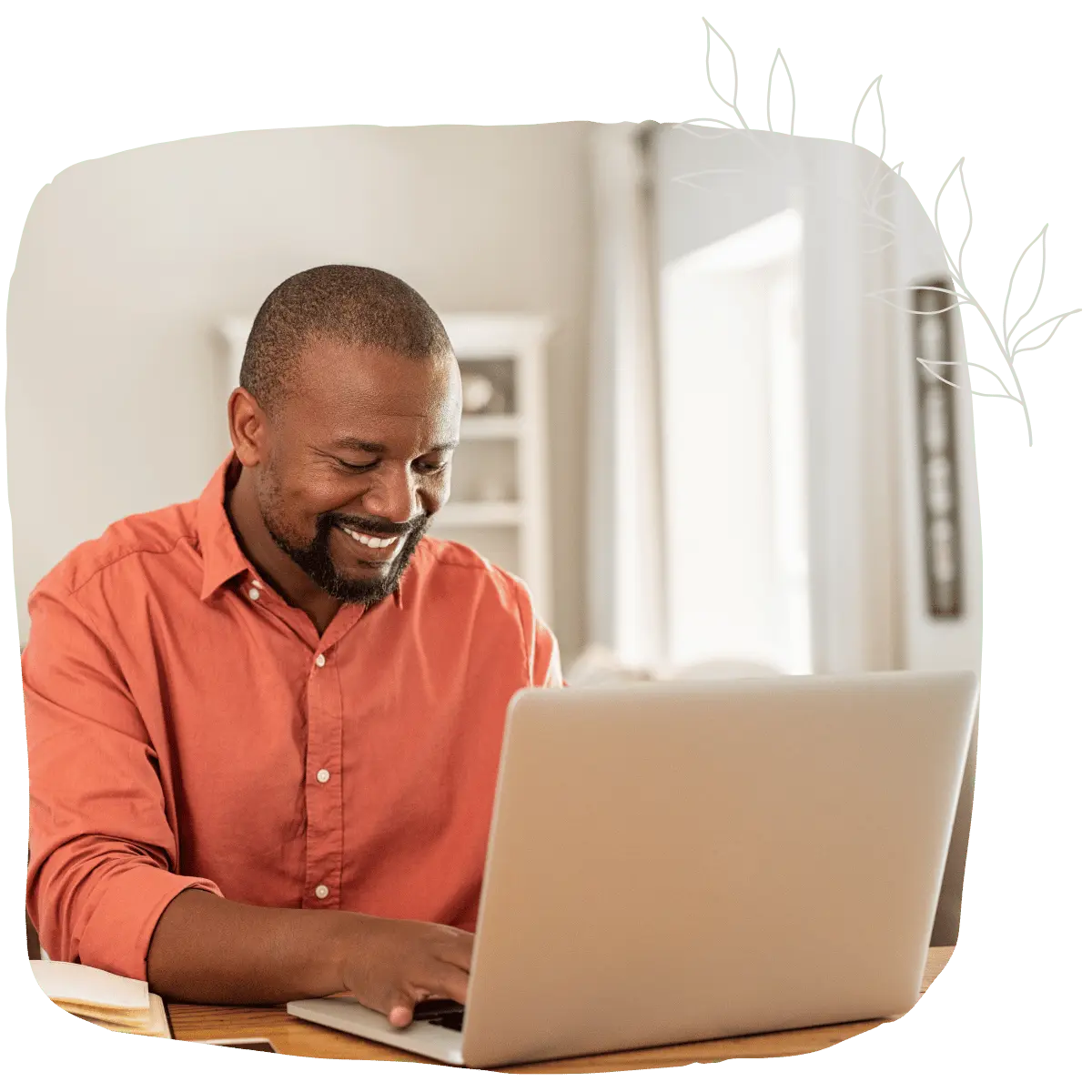 A man smiling while typing on his laptop