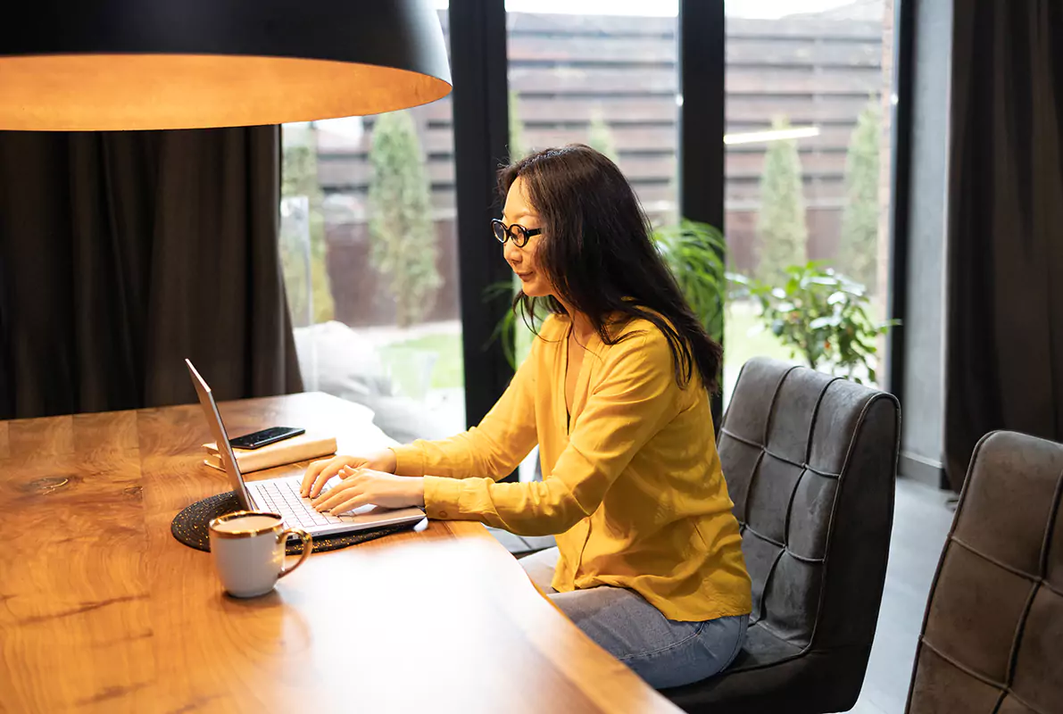 A woman typing on her laptop while sitting down